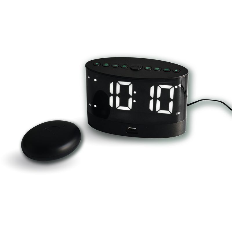 réveil avec grand écran affichant l'heure en chiffres blans sur fond noir et un coussin vibrant posé à côté