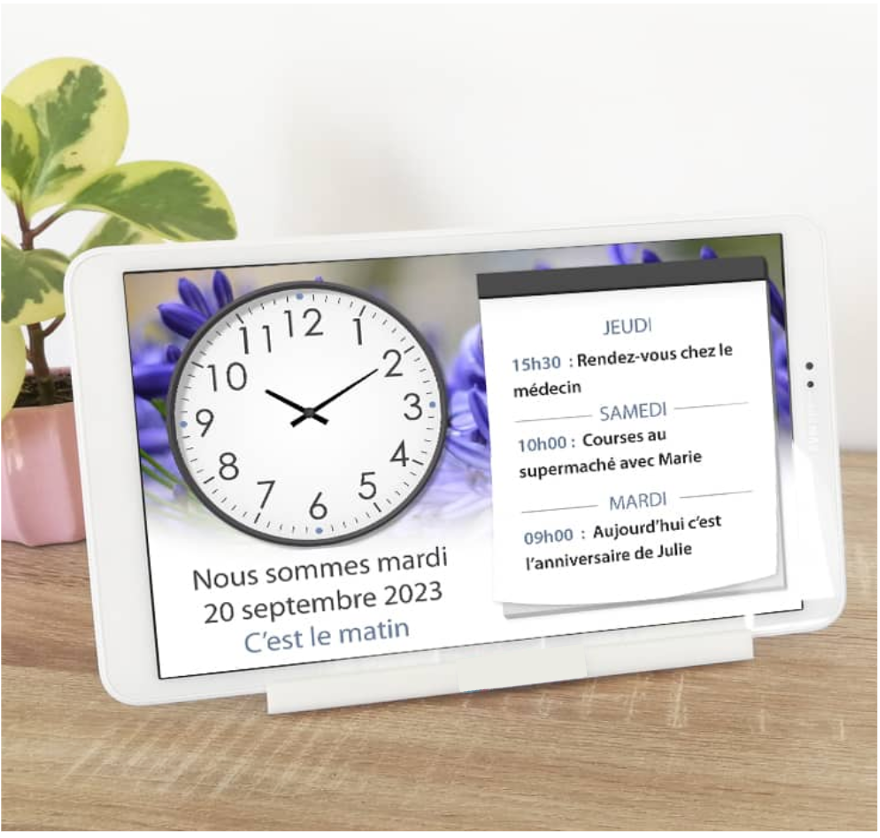 tablette posée sur socle en position paysage montrant à l'écran le cadran d'une horloge à chiffres, la date, le moment de la journée et un agenda de rappels