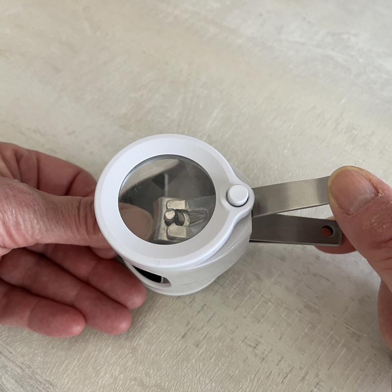 Personne se servant d'un coupe ongles avec loupe et lampe