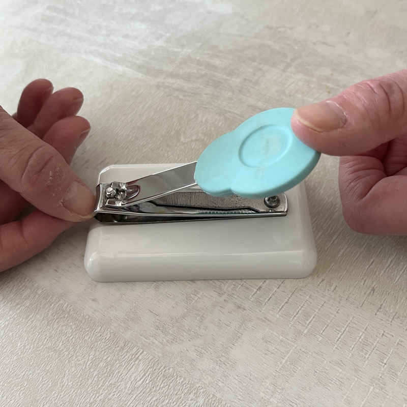 Personne se servant d'un coupe ongle sur socle