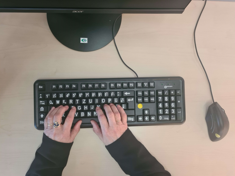mains tapant sur clavier à caractères grossis