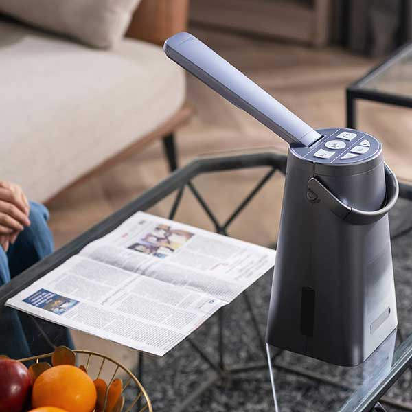 Machine à lire portable posée sur une table basse avec un magazine dessous près à être lu